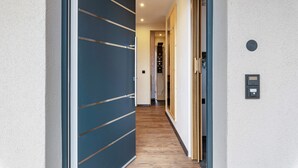 Un pasillo con una puerta azul, piso de madera y un portero automático en la pared.
