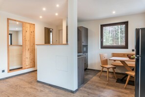 Une cuisine moderne dotée d’un four à micro-ondes encastré, de meubles en bois et d’un coin repas avec une table et des chaises.