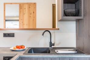 Une cuisine moderne avec des meubles en bois, un évier noir et une planche à découper blanche.