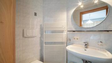 A bathroom with a white radiator, a sink, and a mirror.