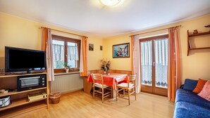 A room with a television, a table with chairs, a sofa, and a window with curtains. - Farmhouse 'Bauernhof Oberkapillhof 2' with Mountain View, Shared Garden and Wi-Fi (Meltina)