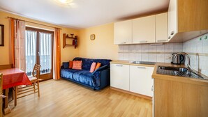 A compact kitchen with a dining area, a sofa, and a window with curtains. - Farmhouse 'Bauernhof Oberkapillhof 2' with Mountain View, Shared Garden and Wi-Fi (Meltina)