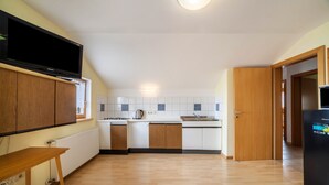 Una cocina moderna con armarios de madera, horno empotrado y un televisor de pantalla plana grande.