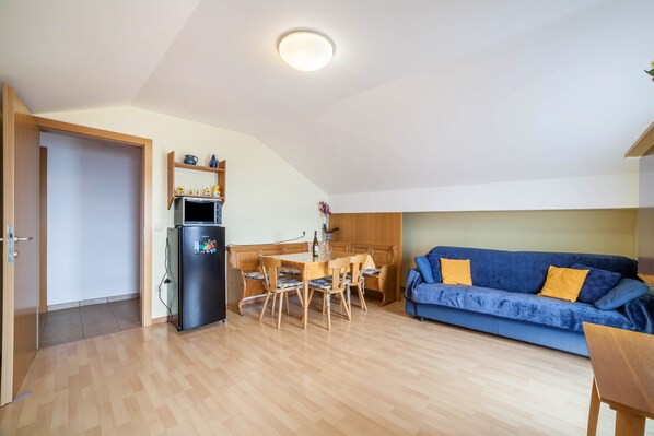 Un espacio habitable compacto con kitchenette, comedor y sofá.