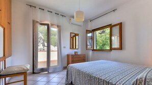 A bedroom with a bed, a chair, a dresser, a mirror, and a window with a view of greenery. - Holiday Home "Castagnola" with Private Garden and Terrace (Marciana)