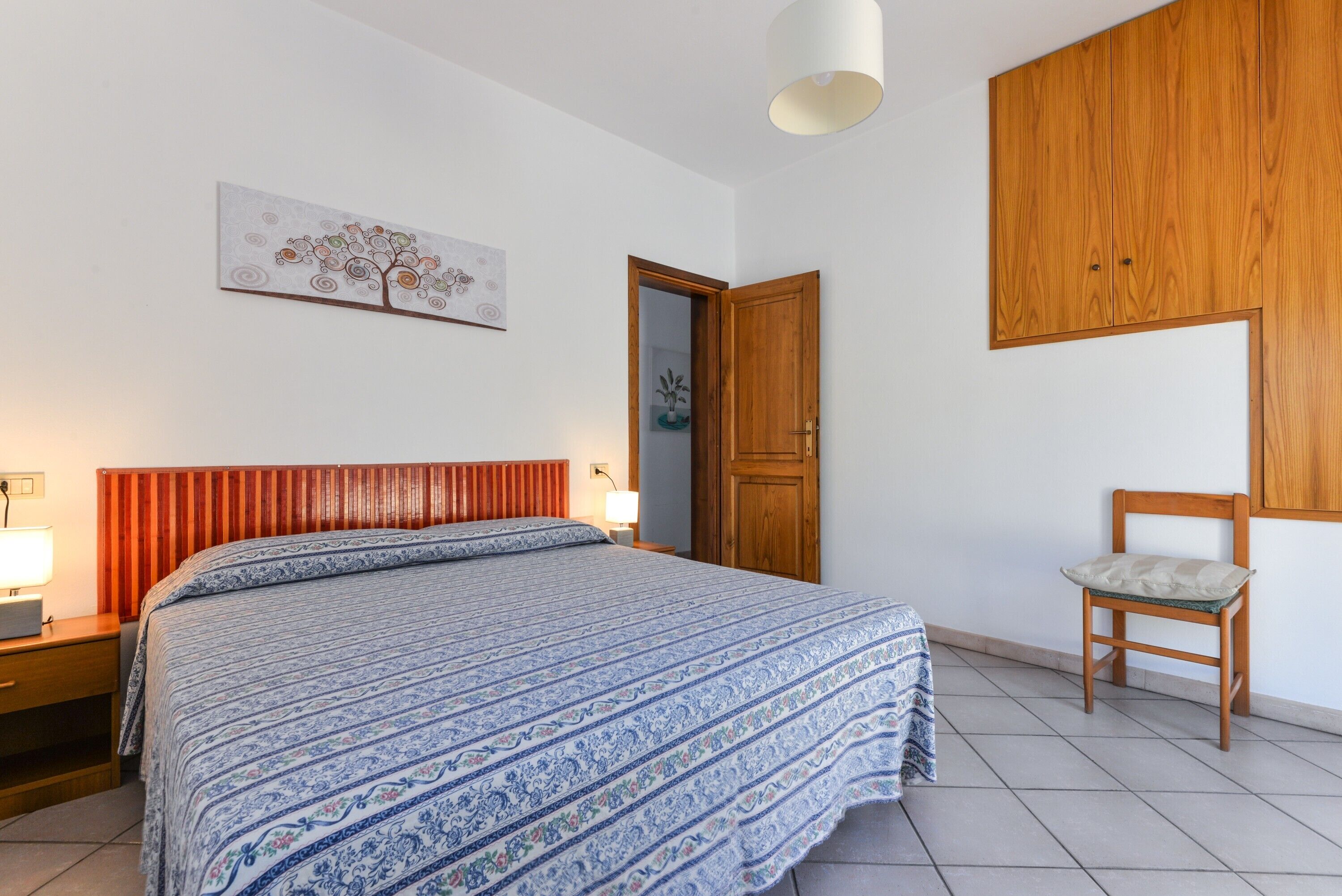 Une chambre à coucher avec un lit, une armoire en bois, une chaise et une porte.