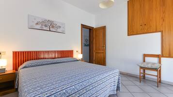 Une chambre à coucher avec un lit, une armoire en bois, une chaise et une porte.