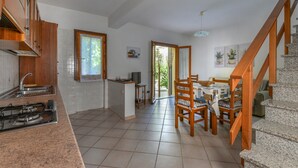 A kitchen with a gas stove, wooden cabinets, a dining area with chairs, a television, and a staircase. - Holiday Home "Castagnola" with Private Garden and Terrace (Marciana)