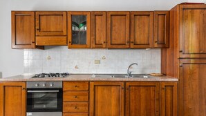 A kitchen with wooden cabinets, a stainless steel sink, and a built-in oven. - Holiday Home "Castagnola" with Private Garden and Terrace (Marciana)