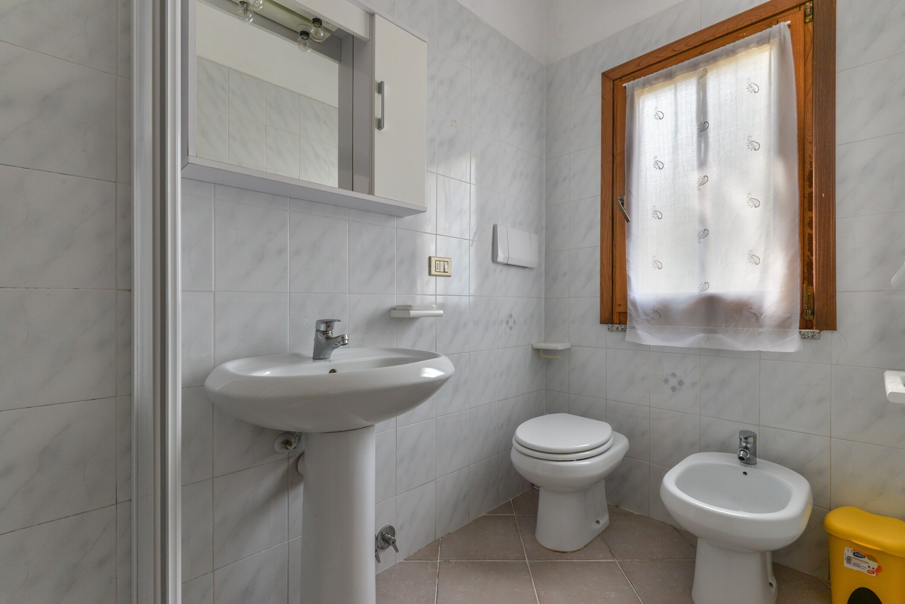 Une salle de bain équipée d’un lavabo, de toilettes, d’un bidet et d’un miroir au-dessus du lavabo.