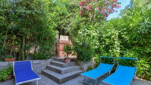 A patio area with two blue lounge chairs and a stone staircase leading to a wooden door. - Holiday Home "Castagnola" with Private Garden and Terrace (Marciana)