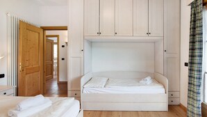 A bedroom with a bed, a wooden wardrobe, and a view of the hallway. - Apartment 'Baita Valandrea 2' with Mountain View, Shared Garden and Wi-Fi (Livigno)