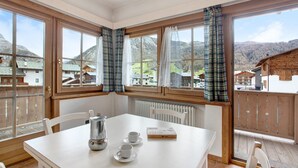 A room with a table, chairs, a radiator, and a window with curtains. - Apartment 'Baita Valandrea 2' with Mountain View, Shared Garden and Wi-Fi (Livigno)