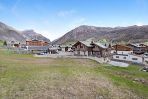 A mountain lodge with multiple buildings, a parking area, and a view of the surrounding mountains.