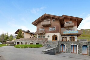 A multi-story building with a ski rental service sign, stone steps, and a wooden balcony.