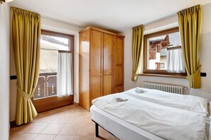 Une chambre à coucher avec un lit, une armoire et une fenêtre avec des rideaux.