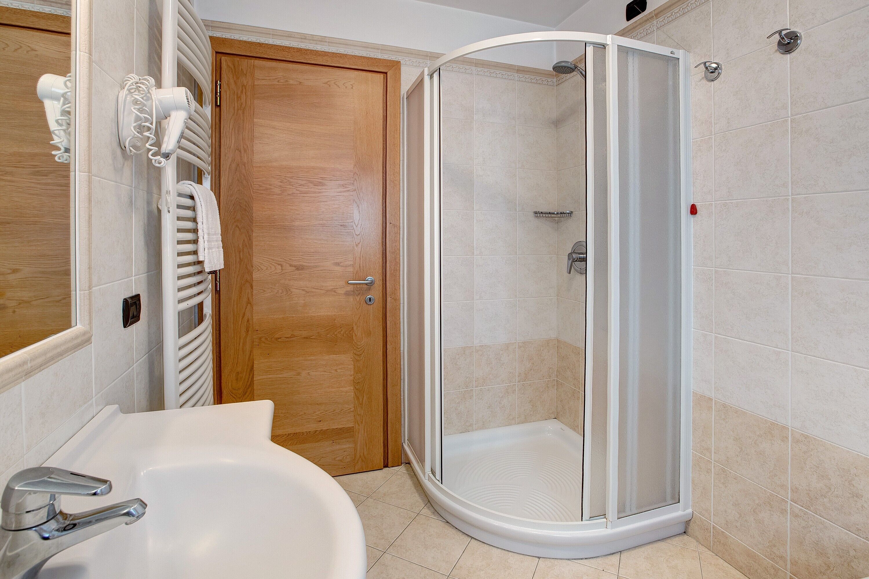 Een badkamer met een douche, wastafel en deur.