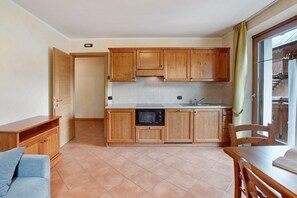 Una cocina con armarios de madera, microondas y comedor con mesa y sillas.