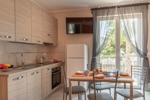 A modern kitchen with wooden cabinets, a built-in oven, a refrigerator, and a dining area with a table and chairs. - Apartment 'Libeccio' with Balcony, Wi-Fi and Air Conditioning (Loano)