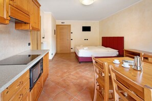 Une pièce compacte comprenant un coin cuisine, un lit, une table à manger et un téléviseur.