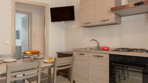 Une cuisine moderne équipée d’un four encastré, d’une cuisinière à gaz et d’un téléviseur à écran plat fixé au-dessus du plan de travail.