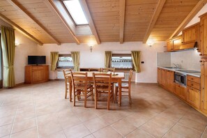 Une cuisine spacieuse avec des meubles en bois, une table à manger avec des chaises, un téléviseur et une lucarne.