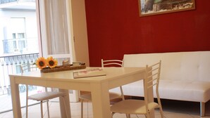 A dining area with a table, chairs, a sofa, a window with a view, and a painting on the wall. - Apartment 'Il Fosso' with Sea View, Wi-Fi (Borghetto Santo Spirito)