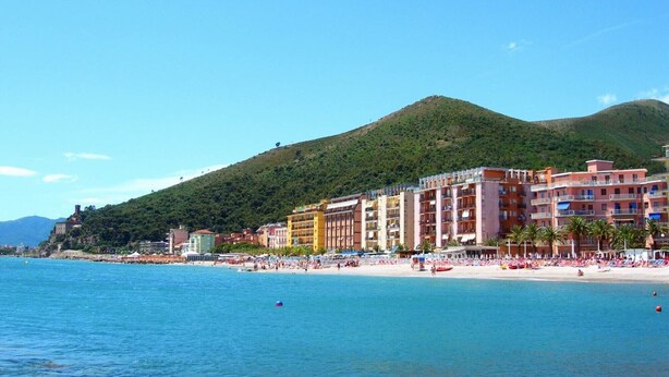 A coastal hotel with multiple floors, a beach in the background, and a hill. - Apartment 'Il Fosso' with Sea View, Wi-Fi (Borghetto Santo Spirito)