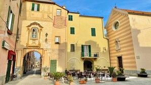 A narrow street with buildings on either side, outdoor seating, and a clear sky. - Apartment 'Il Fosso' with Sea View, Wi-Fi (Borghetto Santo Spirito)