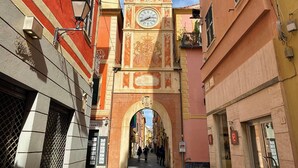 Een smalle straat met een opvallende klokkentoren, een voetpad en gebouwen met traditionele architectuur.