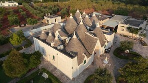 A building with multiple conical roofs, surrounded by greenery and a paved courtyard.