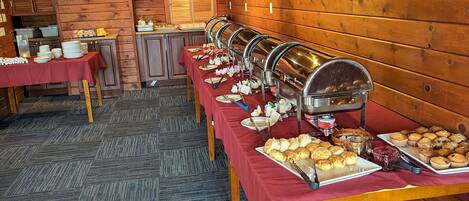 A buffet setup with multiple serving stations, a wooden interior, and a carpeted floor.