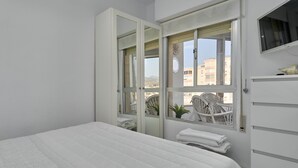 A bedroom with a bed, a window with a view of buildings, a chair, and a small table. - Great Views Studio A84 near the beach with shared pool and Wi-Fi (Torrox)