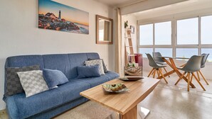 A living room with a blue sofa, a wooden coffee table, and a view of the sea through large windows. - Studio Apartment "Great Sea Views Studio A68" near Beach with Shared Pool & Wi-Fi (Torrox)
