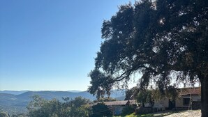 A swimming pool with a view of distant hills, surrounded by greenery and a building. - Country House El Rincón with Mountain Views, Private Pool and 2 Terraces (Arroyomolinos de León)