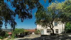 A stone building with a red-tiled roof, a tree in front, and a clear blue sky. - Country House El Rincón with Mountain Views, Private Pool and 2 Terraces (Arroyomolinos de León)
