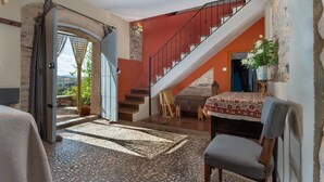 A spacious living area with a staircase, a view through an open archway, and a rustic stone floor. - Country House El Rincón with Mountain Views, Private Pool and 2 Terraces (Arroyomolinos de León)