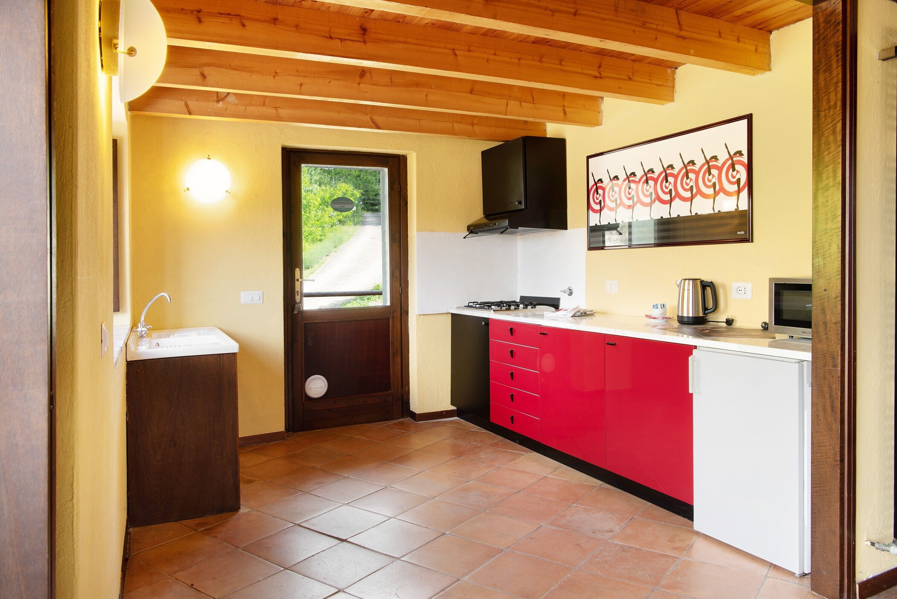 A compact kitchen with a sink, stove, and red cabinets.