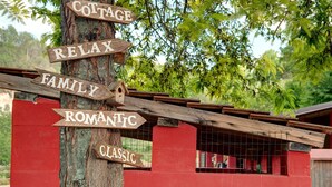 Een houten bord met pijlen en aanduidingen zoals 'COTTAGE', 'RELAX', 'FAMILIE', 'ROMANTISCH' en 'CLASSIC'.