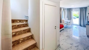 Un interior moderno con una escalera, una zona de comedor y una cocina.