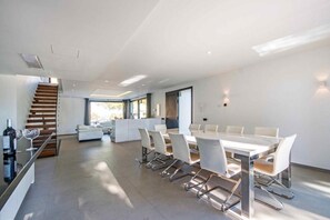 A modern interior with a dining area, white furniture, and a staircase.