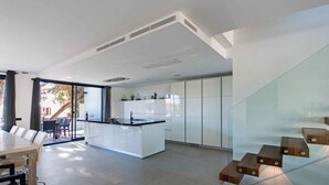 Une cuisine moderne avec des meubles blancs, un îlot central et un coin repas comprenant une table et des chaises.