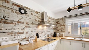 Een keuken met witte kastjes, een backsplash van bakstenen en een inbouwfornuis, met een raam en uitzicht.