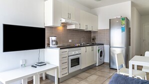 Una cocina moderna con armarios blancos, horno empotrado, lavadora y refrigerador.