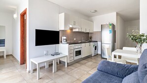 Una cocina moderna con armarios blancos, horno integrado y lavadora.