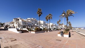 Un edificio costero con balcones, palmeras y cielo despejado.
