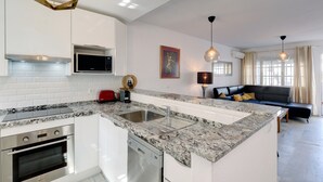 Una cocina moderna con encimeras de granito, electrodomésticos de acero inoxidable e iluminación colgante.