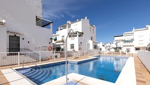 Una piscina en la azotea con un edificio blanco al fondo.