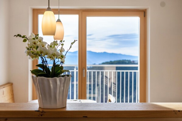 A potted orchid on a wooden table with a balcony view.