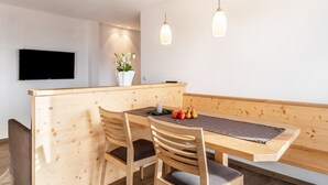 A modern dining area with wooden furniture, a flat-screen TV, and pendant lighting. - Apartment "Reiterhof Gaia" with Mountain View, Private Garden & Wi-Fi (San Genesio Atesino)